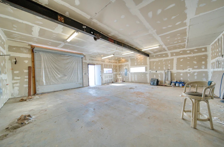 Freshly hung drywall sheets across the walls and ceiling of a room under construction